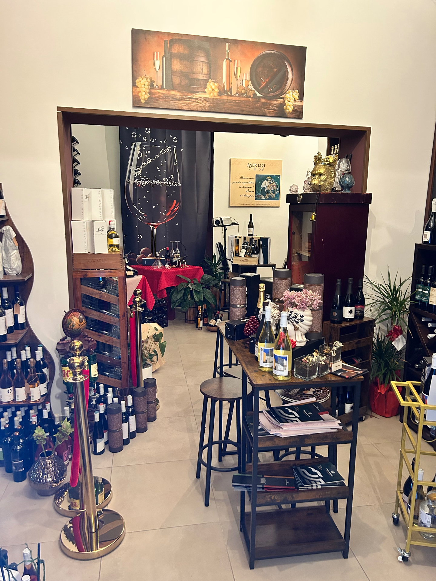 La sala interna del locale con tavolo alto, sgabelli e bottiglie in esposizione