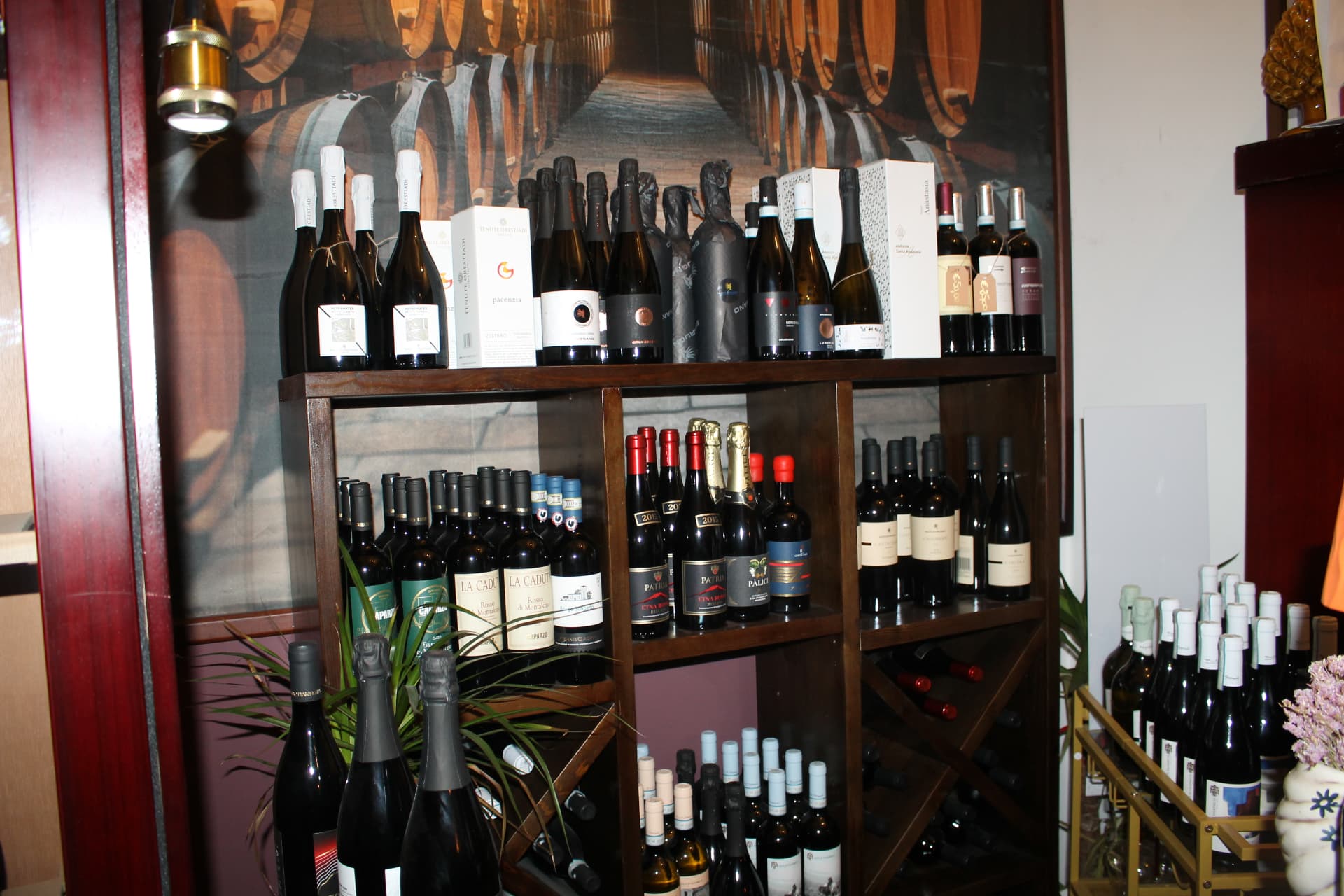 Espositore di vini siciliani e toscani davanti al muro con le botti