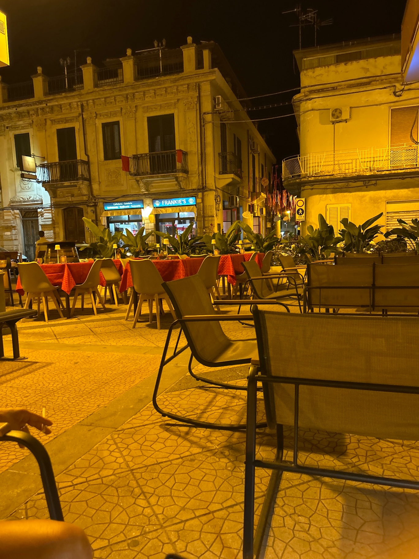 Tavoli all'aperto del wine bar nella piazza di Furci Siculo di sera